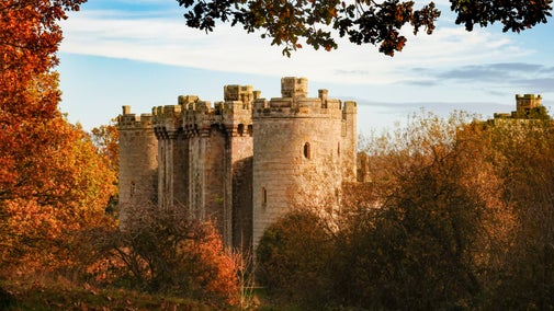 The round, crenellated north-west tower at Bodiam Castle, East Sussex, framed by the autumn colours of the trees